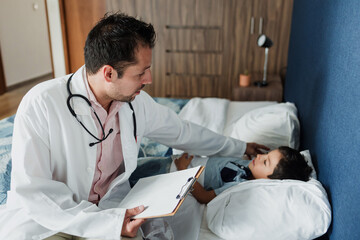 Latin Pediatrician doctor consulting or checking on a child in bed at home in Mexico Latin America, hispanic male doctor consulting patient 