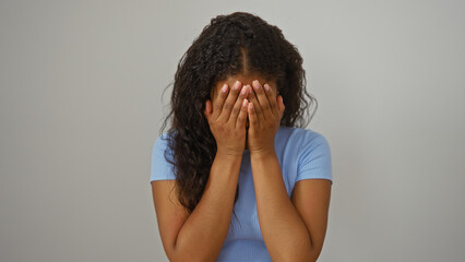 Woman covering face with hands standing over isolated white background, expressing sadness or distress.