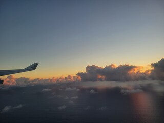 A commercial airplane is gracefully flying through the clouds during sunset