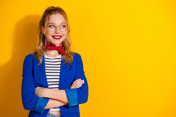 Confident young woman in stylish blue jacket and red scarf standing against bright yellow backdrop
