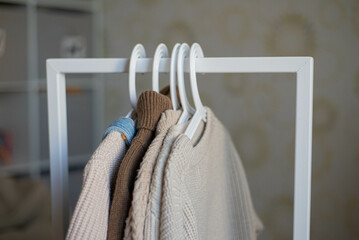 open storage: children's clothes in beige tones hanging on hangers