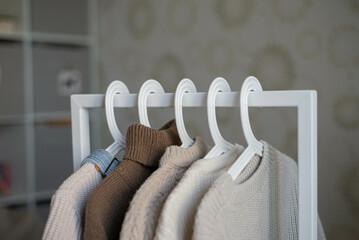 open storage: children's clothes in beige tones hanging on hangers
