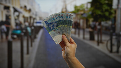 Man counting hong kong dollars on a busy urban street, demonstrating investment and currency...