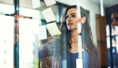 Business woman, writing or meeting with glass board for project planning, tasks or team agenda at...