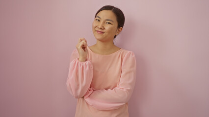 Obraz premium Woman smiling confidently over isolated pink background, showcasing elegance and charm in a serene pose, wearing a light blouse, exuding confidence and grace with a cheerful demeanor.