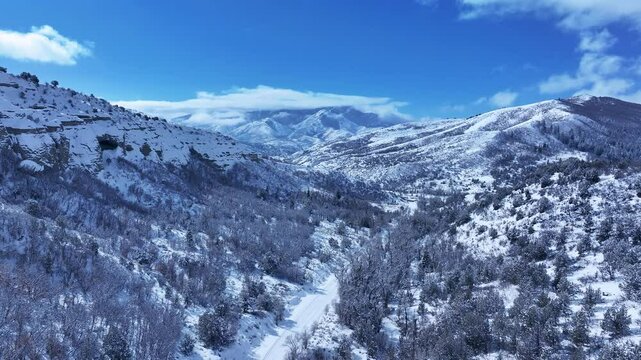 Aerial Mount Nebo Utah winter snow mountain valley. Beautiful late winter Wasatch Mountains. Valley and alpine landscape. Cold weather cloud environment. Rocky ledges, cliffs, canyon and valleys. 