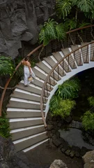 Peel and stick wall murals Woman walking down elegant curved staircase in museo del campesino with lush greenery and volcanic rock backdrop in lanzarote, canary islands