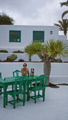 Woman enjoying outdoor cafÃ© at museo del campesino, lanzarote, surrounded by green chairs and white traditional architecture.