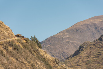 panoramic view of quechua women with traditional clothes walking uphill carrying goods in her back in Bolivia in the andean mountain range town charazani