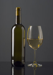 Elegant glass of white wine beside a bottle on a sleek surface