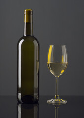 Elegant display of gray beverage in a glass next to a bottle against a dark background