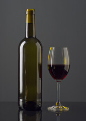 Elegant gray background showcasing a bottle of red wine and a glass