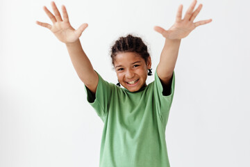 Excited young boy in green tshirt raising hands in trendy celebration pose