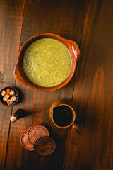 flat lay of creamy green vegetable soup on bowl with rustic elements on wooden background.
