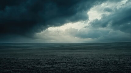 Dramatic dark clouds over a flat, grassy field.
