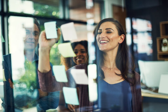Smile, sticky notes and writing on glass with business people in office together for brainstorming. Collaboration, meeting and upskill training with happy colleague group in workplace for discussion