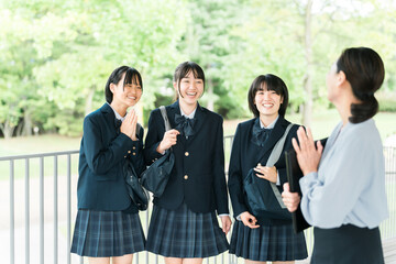 先生に挨拶する笑顔で校舎を歩く仲良しの女子学生（登校・下校・通学）  © buritora