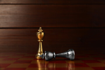 Golden chess king near fallen silver one on chessboard. Competition concept