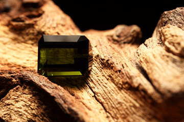 Beautiful shiny green gemstone on stone against dark background