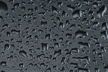 Water drops on black glass surface, closeup
