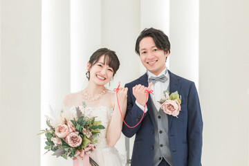 結婚式場で赤い糸で結ばれる新郎新婦（ブライダル・ウェディング）
