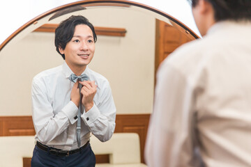 控え室・ブライズルームで結婚式・挙式・披露宴の準備をする新郎・花婿（蝶ネクタイ） 