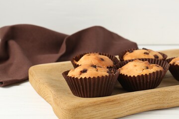 Delicious muffin with chocolate chips on white wooden table, closeup
