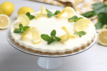 Delicious lemon cheesecake with mint and fresh fruits on white wooden table, closeup