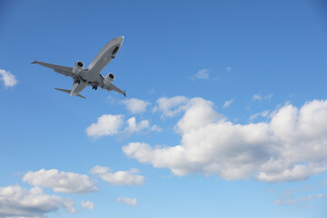 Airplane flying in beautiful blue sky with clouds