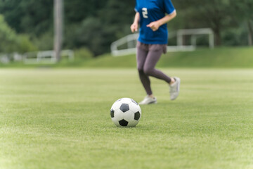 サッカー場でユニフォームを着てサッカー・フットサルの練習をする日本人女性
