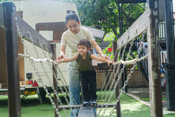 A joyful moment of a parent assisting a child on a playground bridge, showcasing the bond of...