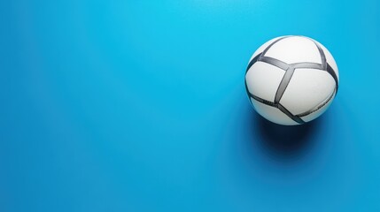 Fototapeta premium Volleyball positioned off-center on a smooth blue background, top-down perspective, no people, sports concept