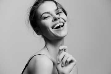 Joyful young woman smiling while playing with her hair, showcasing happiness and confidence against...