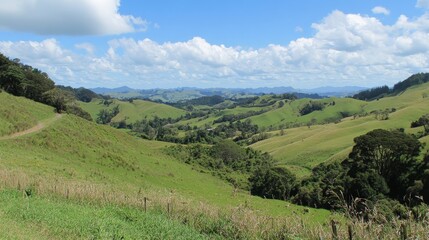 Obraz premium Lush Green Hills Under Bright Blue Sky with Clouds