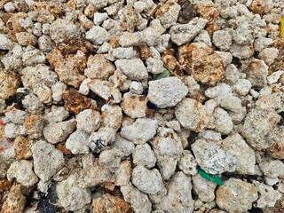 A pile of weathered stones with mixed brown and white hues, scattered naturally