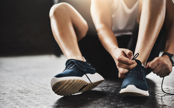 Hands, gym and shoelaces for fitness on floor with start, routine and sneakers for exercise in morning. Person, feet and legs with shoes for workout, wellness and ready at training at health club