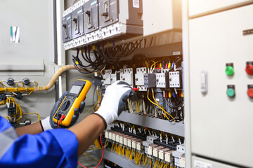 Fototapeta na wymiar Electrical service technician holding electricity checking equipment to check electric current circuit breaker terminal panel and cable wiring main power distribution board for maintenance system.