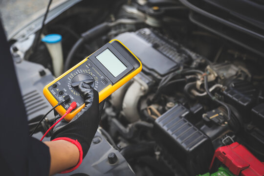 Electrical technician car mechanic use voltmeter to check voltage battery low energy problem for car care service maintenance and re charger or jump start or change battery replacement.