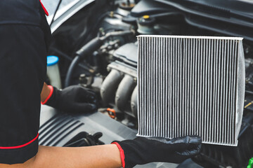 Car care maintenance servicing technician or auto mechanic holding car air conditioner filter for...