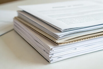 Stack of documents on table, showcasing various paper types and textures