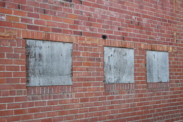 Windows boarded up on brick building.