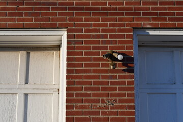 Damaged outdoor lighting on red brick building.