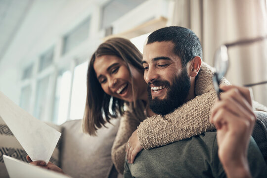 Couple, laptop and documents for finance on sofa, excited or hug for investment, growth or profit in home. Happy, man and woman by pc, celebration or review for budget, income with success in house