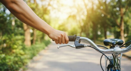 Close-up of person's hand on bicycle handlebar, sunny outdoor path
