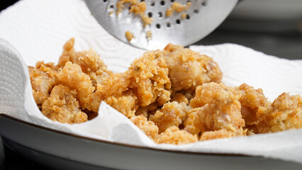 Crispy fried chicken pieces resting on a paper towel, absorbing excess oil, showcasing their golden-brown texture.