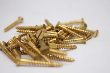 golden brass screws scattered on a white background. Perfect for hardware, construction, repair, DIY, and industrial themes. High-quality macro shot for tools and building materials.
