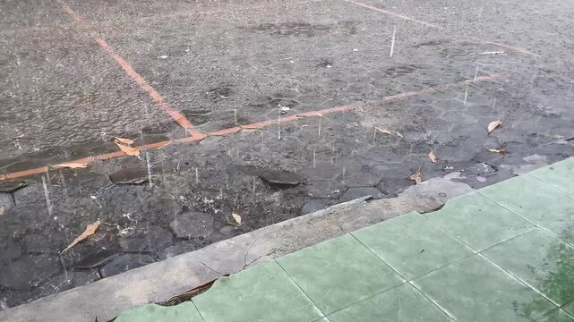 Rainwater falls in front of the elementary school classroom during the day with moderate rain intensity.