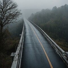 Fototapeta premium A foggy morning view of a long bridge over a wide river, with a road leading off into the mist.