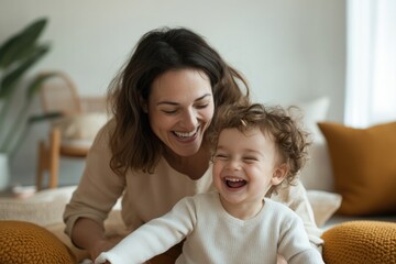 playful moment of mother tickling her child on soft rug in living room surrounded by pillows and laughter leaving space
