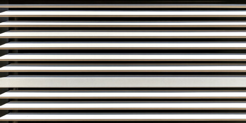 Horizontal slats casting shadows in bright sunlight at a modern building exterior